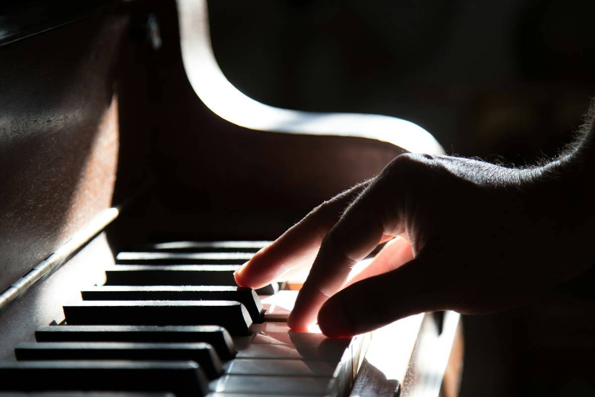 Woman practicing piano music lessons for beginners at home with correct hand posture on digital keyboard