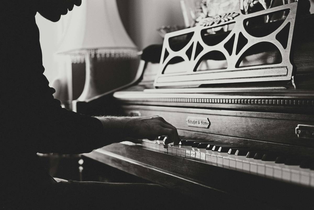A beginner practicing piano at home with sheet music and metronome on the stand, focused on piano practice for beginners
