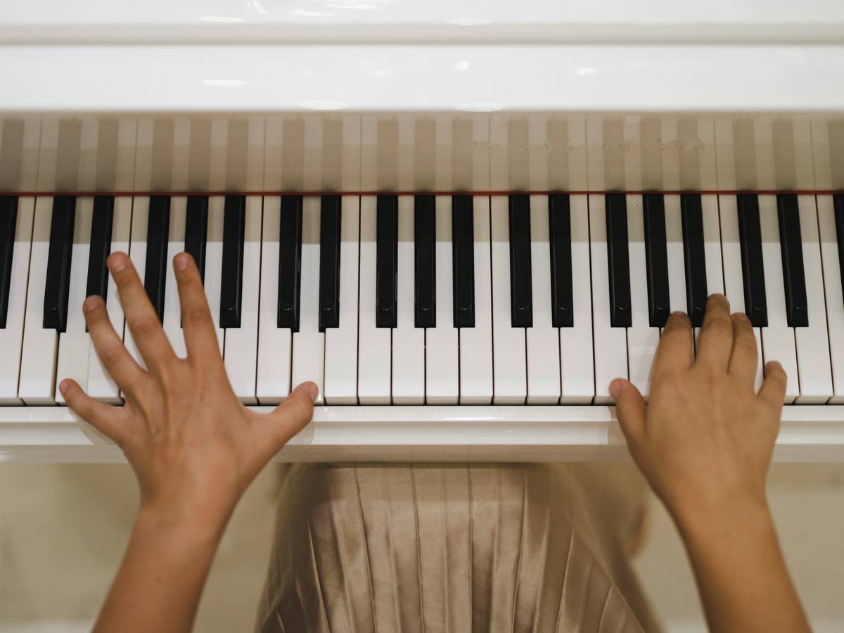 Young adult practicing piano with sheet music, focused expression, illustrating practice technique piano lesson beginner benefit